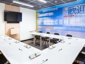 a conference room with white tables and a screen at Ibis Styles Mulhouse Centre Gare in Mulhouse