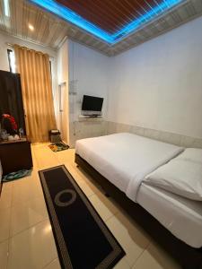 a bedroom with a large white bed and a television at Villa Copenhagen Bukittinggi in Bukittinggi