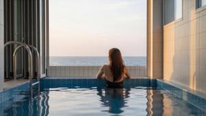 a woman sitting in a swimming pool looking out at the ocean at Pohang Etoile Poolvilla in Pohang