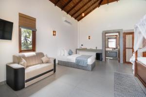 a bedroom with a bed and a couch and a television at Arinna Beach Resort in Tangalle