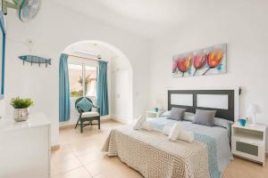 a white bedroom with a bed and a chair at Villa Pearla by Villa Plus in Cala en Porter +11 photos