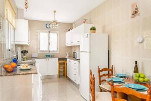 a kitchen with a table and a white refrigerator at Villa Pearla by Villa Plus in Cala en Porter