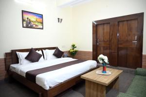 a bedroom with a large bed and a wooden door at Panch Aarohan Hotel King in Pithorāgarh
