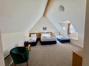 a attic room with two beds and a green chair at Purbeck House Hotel & Louisa Lodge in Swanage