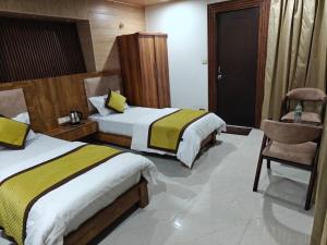 a hotel room with two beds and a chair at The Himalayan Majesty Hotel in Chopta