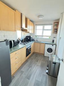 a kitchen with wooden cabinets and a washer and dryer at Cosy one bed Flat in Stevenage in Stevenage +6 photos
