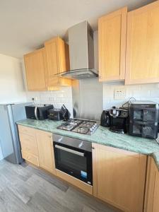 a kitchen with wooden cabinets and a stove top oven at Cosy one bed Flat in Stevenage in Stevenage