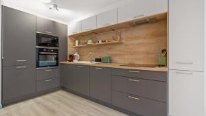 a kitchen with gray cabinets and wooden walls at Bel Apt neuf - HyperCentre 400m Plage-Pkg-Wifi-T3 in Arcachon +2 photos