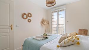 a white bedroom with a bed with pillows and a window at Bel Apt neuf - HyperCentre 400m Plage-Pkg-Wifi-T3 in Arcachon