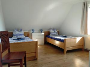 two beds in a room with a chair and a table at Apartment Zausel in Bad Münder am Deister +6 photos