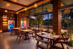a restaurant with wooden tables and chairs and a large window at Shakuntalam Sagar - Luxury Boutique Lake View Hotel, Udaipur in Udaipur