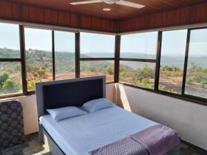 a bedroom with a bed in a room with windows at Sattva Gruha in Māngaon