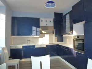 cocina con armarios azules, mesa y sillas en Villa D'ALBATRE en Dieppe