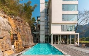 a house with a swimming pool next to a building at The Dragons Rest Sanctuary-Yulong River Branch - Infinity Pool & Cafe - English Speaking Service - Free MTB Rental & Tailor-Made Tour Service in Yangshuo