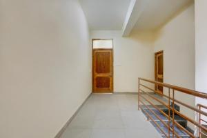a hallway with a wooden door and a staircase at Hotel O Model Town Road in Manāli