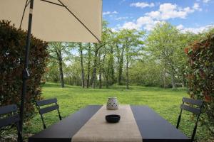 a table and chairs with an umbrella in a yard at Maison cosy 6 pers - piscine chauffée - nature et lac - Monflanquin in Monflanquin
