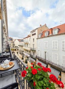a balcony with a table and red flowers on a balcony at Appart de charme, centre Vichy, Thermes in Vichy