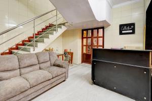 a living room with a couch and a staircase at Collection O Vadapalani Formerly Mahalakshmi Inn in Chennai
