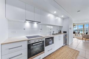 a white kitchen with a sink and a stove at Salt & Sea in Airlie Beach