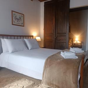 a bedroom with a white bed with a wooden door at Oianthis house in Galaxidi