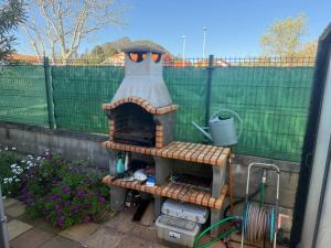 a outdoor oven in a garden with a fence at Casa Santiago in Argoños