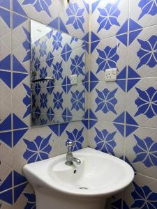 a bathroom with a sink and blue and white tiles at Arizona apartment in Zanzibar City