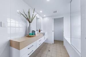 a bathroom with a sink and a vase with a plant at Salt & Sea in Airlie Beach +9 photos