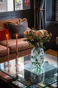 a vase with flowers on a glass table with two candles at The Tophams Hotel in London
