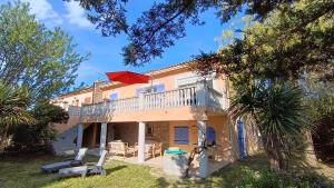 a house with a balcony with a red umbrella on it at Maison au calme avec jardin et piscine Saint Raphaël in Saint-Raphaël