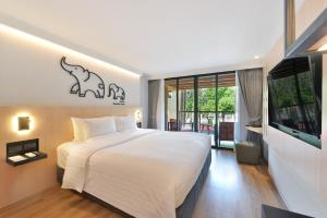 a bedroom with a large white bed and a window at March Hotel & Suite Riverside in Chiang Mai