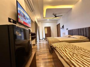 a hotel room with two beds and a flat screen tv at Hotel Jatra in Sillod