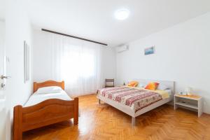 a bedroom with two beds and a wooden floor at Nikola's spacious apartment in Božava