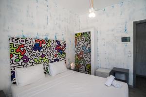 a bedroom with a white bed with a colorful wall at Beach Boutique Hotel in Kamari +45 photos