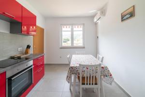 a kitchen with red cabinets and a table with chairs at Nikola's spacious apartment in Božava