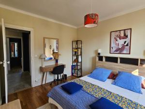 a bedroom with a bed with blue pillows and a desk at La Roseraie in Le Mans