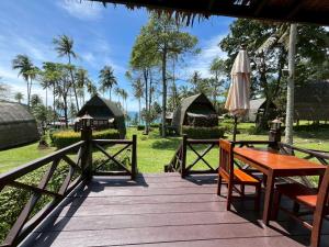 a wooden deck with a table and an umbrella at Koh Kood Beach Resort in Ko Kood