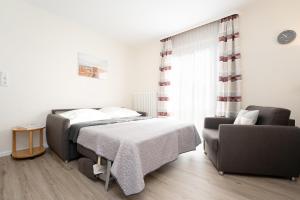 a bedroom with a bed and a couch and a chair at Haus Tweeflunken Wohnung 1 in Kellenhusen +31 photos