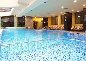 a large swimming pool in a hotel with chairs at St George Ski & Holiday - Half Board & All Inclusive in Bansko