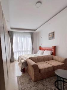 a bedroom with a large bed and a couch at Sharz Cozy studio - Westlands in Nairobi