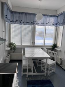 a dining room with a white table and chairs at Hostelli Palonkortteeri in Ilmajoki +13 photos