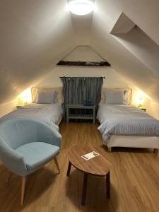 a attic bedroom with two beds and a chair at Apartmány Tachov in Tachov