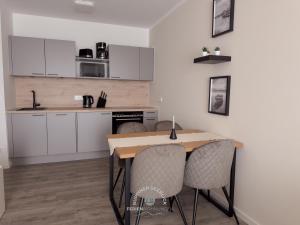 a kitchen with white cabinets and a table and chairs at Ruppiner Seeblick Ferienwohnungen in Neuruppin