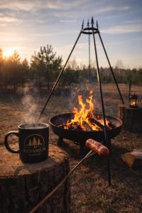 a hot dog and a cup of coffee next to a fire at Silvarium Kaszuby Domek Sosna in Stężyca