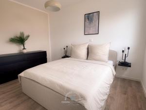 a bedroom with a large bed with white sheets and pillows at Ruppiner Seeblick Ferienwohnungen in Neuruppin
