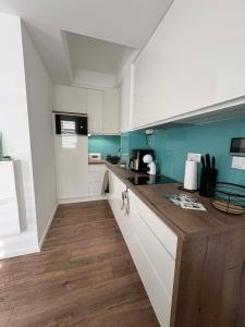 a kitchen with white cabinets and a wooden counter top at H&H Apartman in Fonyód