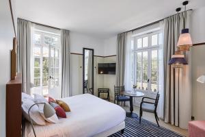 a bedroom with a bed and a table and windows at Villa Arthus-Bertrand in Noirmoutier-en-l'lle +49 photos
