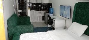 a bedroom with a bed and two green chairs at Starla, Duplex in Nairobi