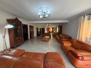 a living room with brown leather couches and a chandelier at GuestHouse Mendrika in Talata-maty