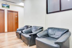 two leather chairs in a room with a door at Super Collection O Pashan-Sus Road Baner Formerly Grey Stone in Pune