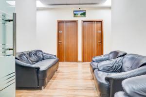 two leather couches in a living room with wooden floors at Super Collection O Pashan-Sus Road Baner Formerly Grey Stone in Pune